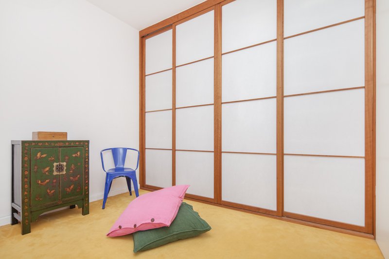 Raumhoher Schiebetürschrank mit Rahmen aus Nussbaum und hellen Feldern aus Shoji-Papier, davor Sitzkissen