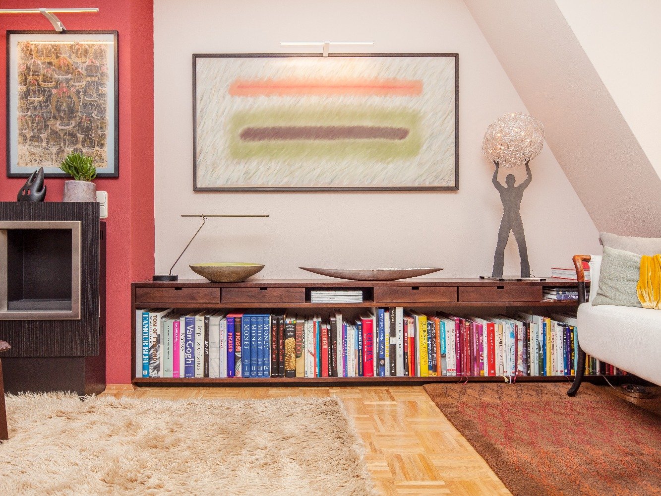 Niedriges Sideboard aus Nussbaum unter einer Dachschräge, darauf Bücher und Dekoration
